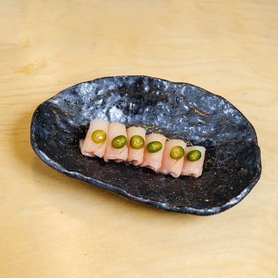 Suki yellowtail jalapeño sashimi on a black plate